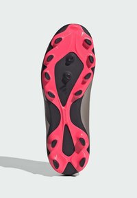 La suela de los tacos de fútbol presenta una parte superior negra con una suela de goma rosa, clavos moldeados y una superficie texturizada para un agarre en diversos tipos de terreno.