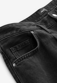 Sorte denim jeans med standard talje, forlommer og metalbeslag til lukning. Tekstureret stof med synlige syninger.