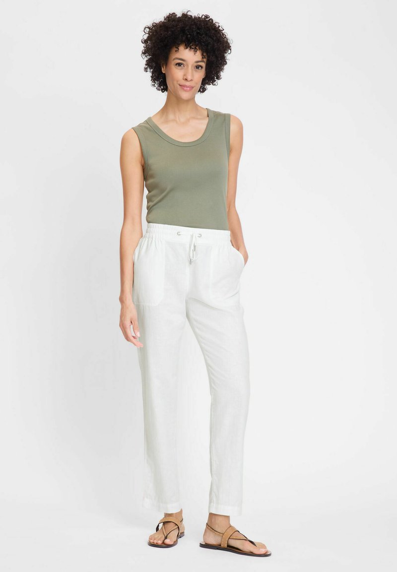 Lightweight olive tank top, white linen pants with elastic waistband and pockets, worn with tan flat sandals, set against a plain background.