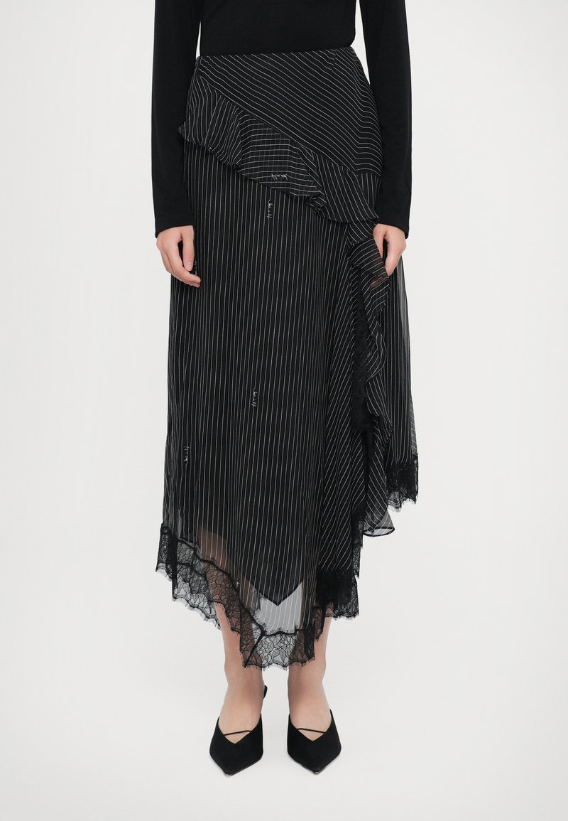 Falda a rayas en blanco y negro con dobladillo con volantes, borde de encaje y diseño asimétrico. Combinada con tacones negros de punta afilada.