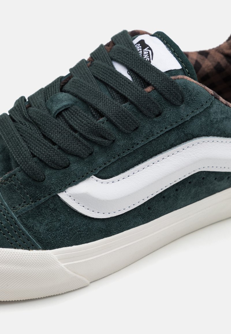 Baskets en suede vert avec des accents en cuir blanc sur les côtés, des lacets texturés et un doublage intérieur à carreaux. Semelle en caoutchouc à profil bas.