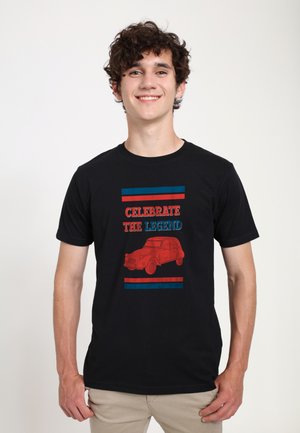 Sort bomulds-t-shirt med grafisk tryk af en rød vintage bil. Teksten siger "FEJR LEGENDEN" med blå og røde striber over og under.