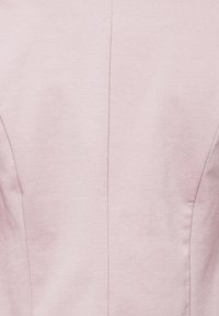 Tissu rose doux avec une couture verticale centrale et des coutures discrètes en pince pour le contour et l'ajustement.