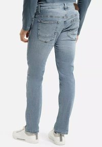 Jasnoniebieskie dżinsy slim fit z pięcioma kieszeniami, kontrastowym szyciem oraz brązową skórzaną naszywką na tylnym pasku.