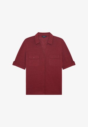 Tummanpunaisesta teksturoidusta kankaasta valmistettu lyhythihainen kauluspaita, jossa on kaksi rintataskua ja nappiluettelo, sekä käännetyt hihansuut.