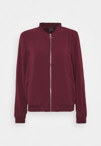 Burgundská bomber bunda se zipem vpředu, stojáčkem a pletenými manžetami. Vyrobená z hladkého materiálu, má boční kapsy a volnější střih.