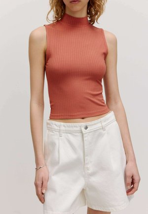 Rust-colored ribbed sleeveless top with a mock neck, paired with white high-waisted shorts featuring a front button and structured fit.