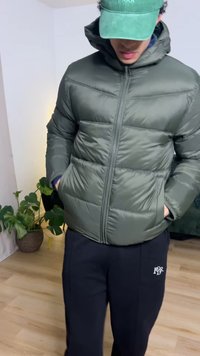 Olivgrön vadderad jacka med dragkedja, huva och två sidofickor. Bärs med svarta sweatpants med en liten logotyp.