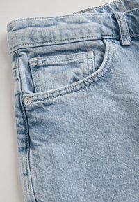 Light blue denim jeans, featuring a front pocket with metal rivet accents, visible stitching, and a slightly faded texture.