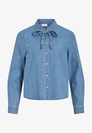 Chemise en denim bleu clair à manches longues avec des boutons-pression argentés sur le devant et un nœud noué au col.