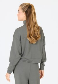Grijze cropped sweatshirt met een hoge kraag, losse pasvorm en verlaagde schouders. Zachte textuur met minimale stikdetails.