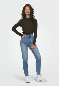 Dark ribbed long-sleeve top paired with light-wash high-waisted jeans and white sneakers. The top features a scalloped neckline and cuffs.