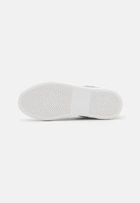 Sole di sneaker bianca con motivo a spina di pesce, texture liscia e punta arrotondata. Design minimalista senza marchi o accenti visibili.