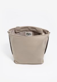 Beżowa skórzana torba typu tote z brązowymi wstawkami po bokach, otwartym wierzchem i wewnętrzną kieszenią na zamek. Zawiera metkę z logo wewnątrz; minimalistyczny design.