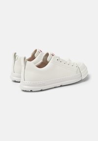 White sneakers with a smooth finish, featuring lace-up closure and a minimalistic design. The logo is on the tongue, with a soft insole.