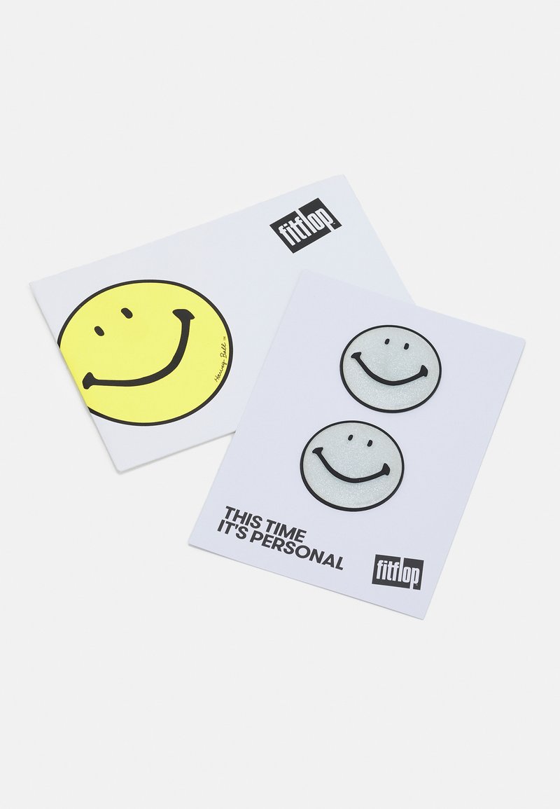 Duas cartas com designs de rostos sorridentes; uma amarela com um contorno preto, outra branca com um sorriso cinzento brilhante. O texto diz: "Desta vez é pessoal."