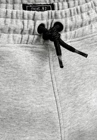 Grå sweatpants med elastisk midjeband och svart dragsko. Har en subtil struktur och sydda sömmar. Lappen säger "next .82."