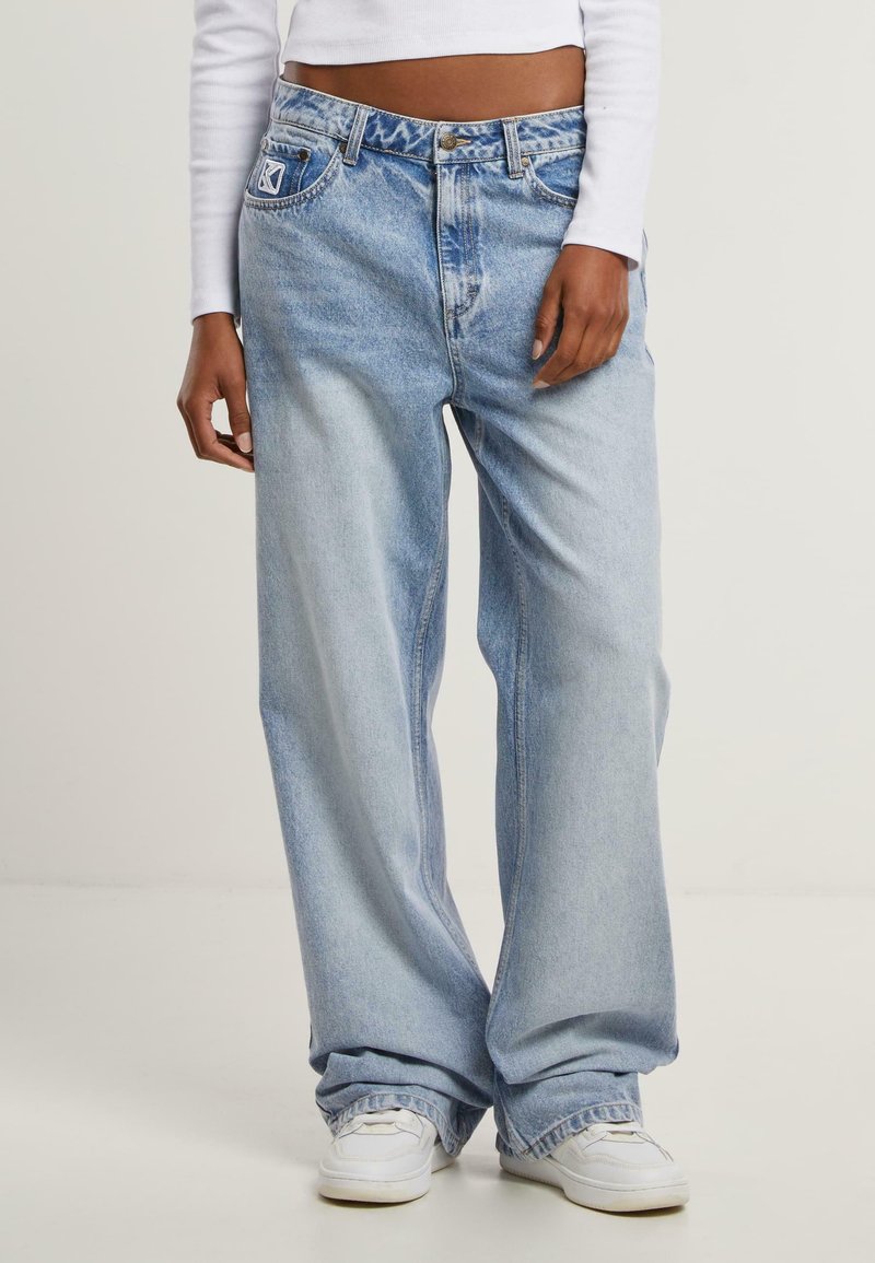 Jeans wide-leg de un albastru deschis, din denim, cu talie înaltă, design tradițional cu cinci buzunare și textură decolorată, cu ușoare urme de uzură.
