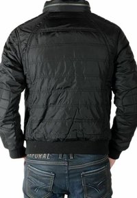 Sort dunjakke med quiltet tekstur, ribbet krave og manchetter. Båret med blå jeans med syningsdetaljer og baglommer.