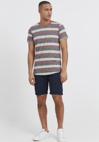 Striped short-sleeve t-shirt in cream, navy, and burgundy; paired with navy shorts. Finished with rolled hems and white sneakers.