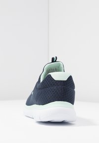 Black mesh athletic shoe with a mint green heel and sole, featuring a pull tab, textured fabric, and a lightweight design.