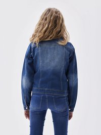 Blå denimjakke med en tettsittende design, knappelukkinger og en lett falmet tekstur; kombinert med matchende blå denimbukser.