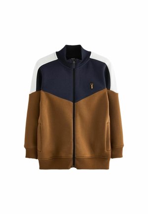 Veste marron, bleu marine et blanche à fermeture éclair, col et poignets côtelés, poches avant et petit emblème tête de cerf sur la poitrine.