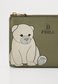 Green leather wallet featuring a cartoon bear design in cream and light blue, with a gold zip and embossed "FURLA" logo.