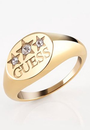 Goldener Ring mit ovaler Fläche, graviert mit GUESS und drei Sternformen, jeweils mit einem klaren Edelstein besetzt.