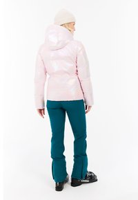 Iridescent rosa pufferjacka med huva, i kombination med tealbyxor. Jackan har quiltade sektioner och byxorna är åtsittande vid vristerna.