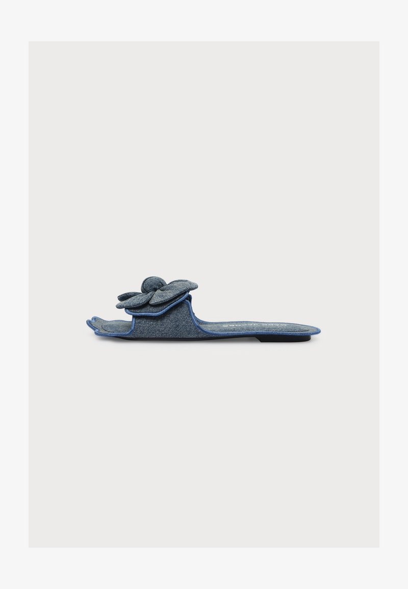 Chausson bleu plat à bout ouvert avec une grande fleur en tissu décorative sur le dessus, présenté de côté sur un fond blanc uni.