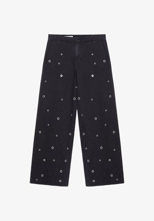 Schwarze, weit geschnittene Hose mit verstreuten silbernen Metallösen und einer vorderen Reißverschlussöffnung vor weißem Hintergrund.