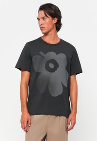 T-shirt in cotone nero con un grande design floreale grigio sulla parte anteriore, maniche corte e scollatura rotonda.