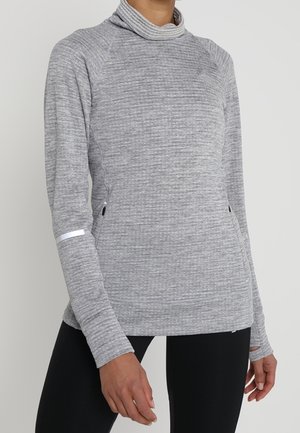 Szara sportowa bluzka z długim rękawem, wysokim kołnierzem i otworami na kciuki, noszona z czarnymi legginsami, pokazana na osobie od szyi do bioder.