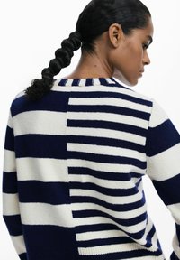 Maglione a righe blu navy e bianche, con strisce di diverse larghezze e colletto a costine. Tessuto morbido a maglia con vestibilità comoda.