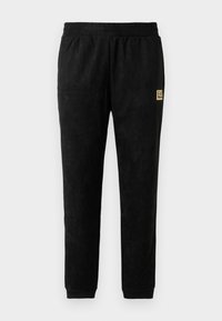 Melni velūra sporta bikses ar elastīgu jostu, aprocēm pie potītēm, sānu kabatām un mazu beigu EA7 Emporio Armani logo uz augšstilba.