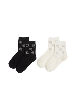 Schwarze und crèmefarbene Knöchelsocken mit einem sich wiederholenden grafischen Design. Das schwarze Paar hat einen dunklen Hintergrund mit grauen Motiven; das crèmefarbene Paar hat einen hellen Hintergrund.