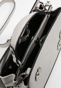 Vaaleanharmaa nahkakäsilaukku, jossa on teksturoitu pinta, mustat yksityiskohdat, kaksoisosiot ja hopeinen varustus, kukkateema. 