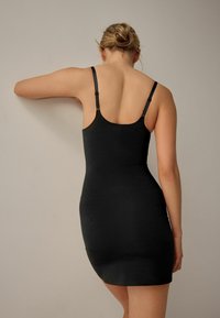 Čierne bodycon šaty s nastaviteľnými ramienkami. Hladká textura, dizajn po kolená, s priliehavou siluetou a minimalistickým štýlom.