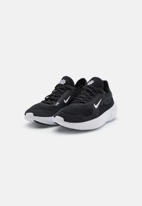 Zapatillas deportivas negras con un upper de malla texturizada y transpirable, y suela de goma blanca en contraste. Presentan un diseño elegante y un logo prominente.
