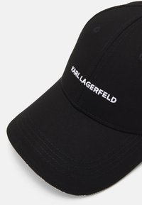 Crna bejzbol kapa od pamuka, s zakrivljenim vizirjem i bijelim izvezenim logom "KARL LAGERFELD" sprijeda.