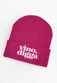 Pink knit beanie featuring a white graphic patch with the text "vino, digga." The hat has a fitted, textured design for warmth.