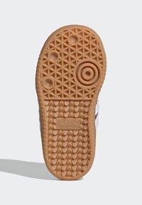 Suela de zapato de goma natural con un patrón texturizado, que presenta un elemento de diseño circular y un logo en relieve de «adidas».