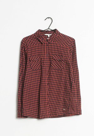 Camisa a cuadros en rojo y negro, material de algodón, diseño abotonado, dos bolsillos en el pecho, cuello puntiagudo y mangas largas.