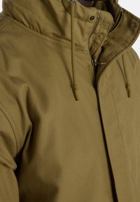 Olive green jacket featuring a zip and snap closure, adjustable hood with drawstrings, and a textured fabric.