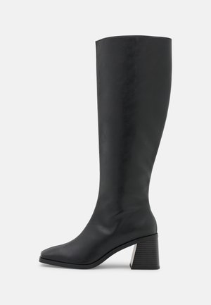 Bottes noires montantes en cuir lisse, avec un bout carré et un talon épais texturé. Le design est épuré et ajusté.