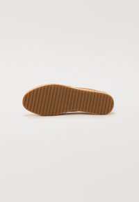 Semelle en caoutchouc marron avec des rainures horizontales et un motif texturé ; forme ronde conçue pour l'adhérence et la durabilité.