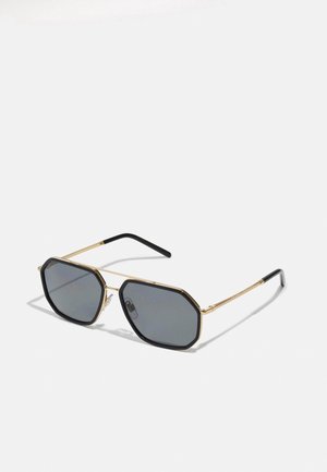 Octagonal sunglasses with dark lenses. Gold metal frame with black accents and textured temples. Sleek and lightweight design.