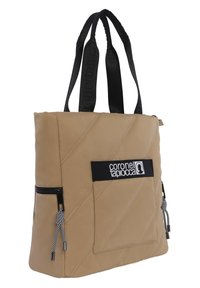 Bolso de tote acolchado en color tan con asas negras, que presenta un bolsillo frontal con una banda de logo negra y cierre de cremallera. Acentuado con cuerdas de tiro a rayas.