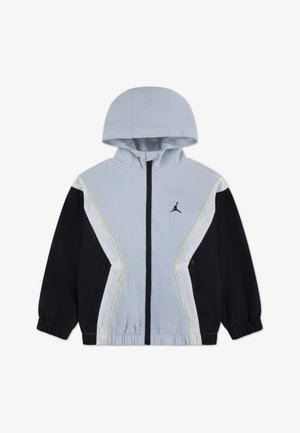 Šviesiai pilka vėjui atspari striukė su juodomis rankovėmis, baltais ir neoninės geltonos spalvos akcentais, užtrauktuku, reguliuojama gaubtu ir tinklinės medžiagos pamušalu.